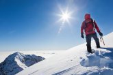 Mountaineer reaches the top of a snowy mountain in a sunny winte Mountaineer reaches the top of a snowy mountain in a sunny winte